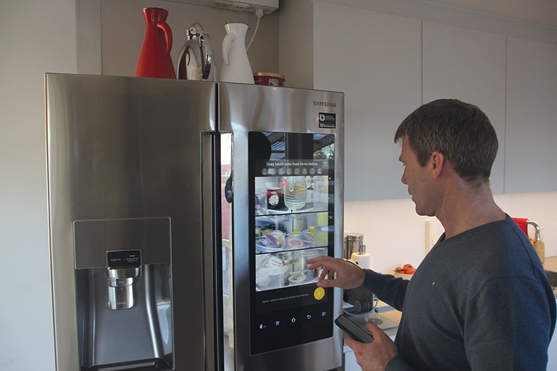 Tre høyoppløselige kameraer tar bilder av innholdet i kjøleskapet. JAn Helge HAgland viser hvordan det ser ut på kjøleskapsskjermen og på mobiltelefonen sin.